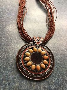 Brown pendant on multiple strands of brown/red strings