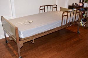Motorized hospital bed with mattress and rails